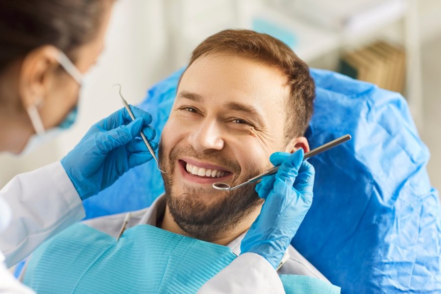 Patient smiling during a dental checkup while a dentist examines teeth and gums, highlighting preventive care for healty gums – healty gums